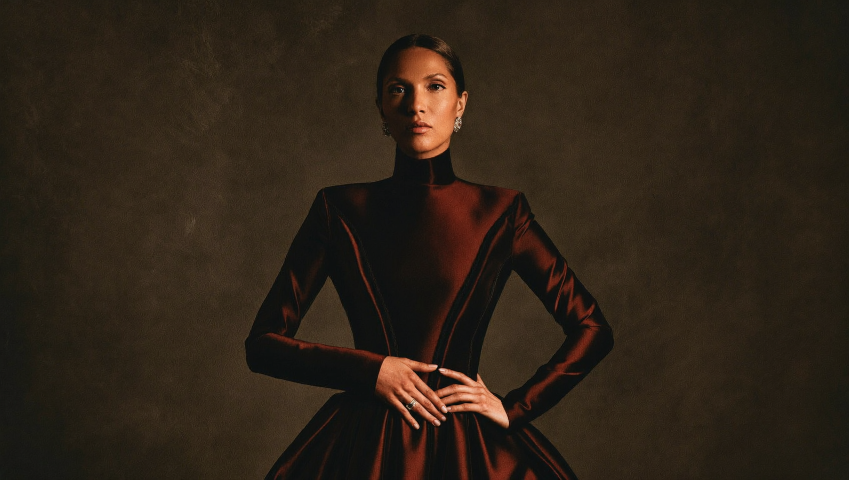 An elegant woman in a black gown in dramatic warm studio light