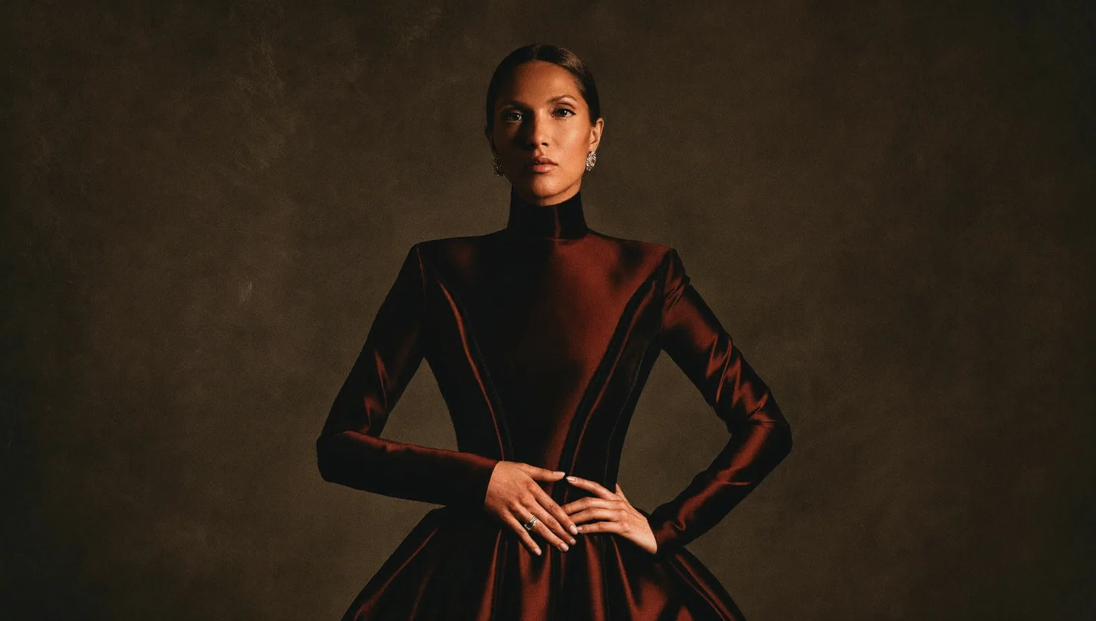 An elegant woman in a black gown in dramatic warm studio light