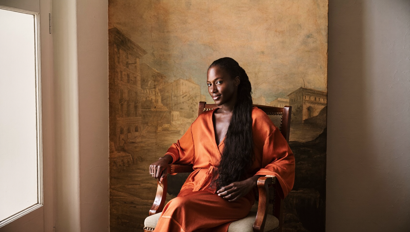 A woman in a flowing silk robe seated in soft window light
