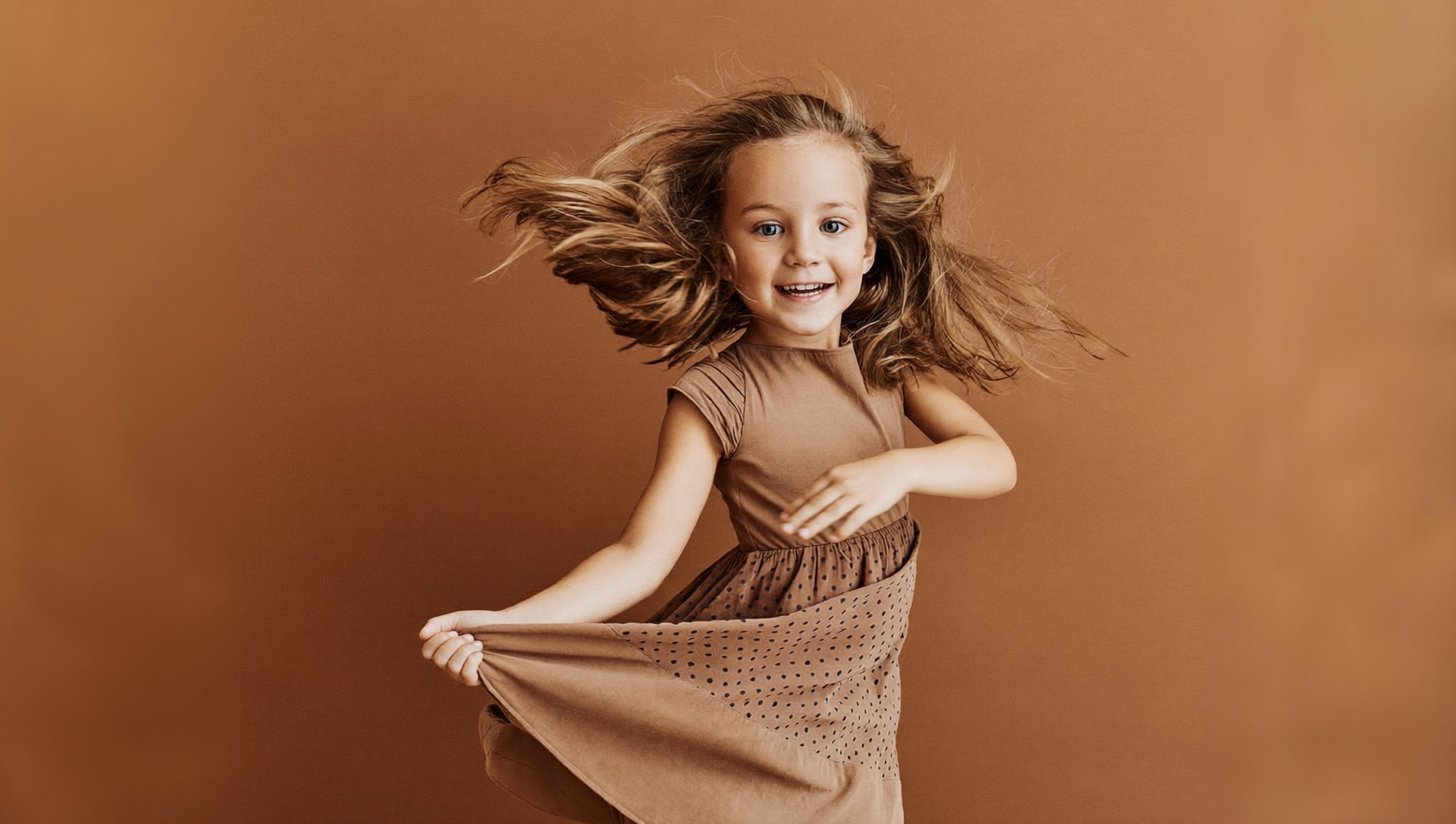 A young girl mid-twirl in a flowing dress during a studio portrait session