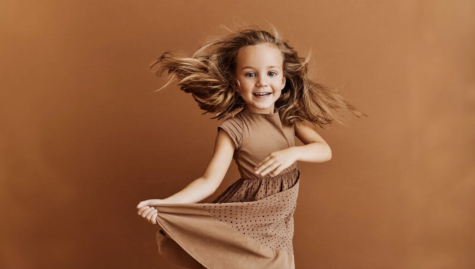 A young girl mid-twirl in a flowing dress during a studio portrait session