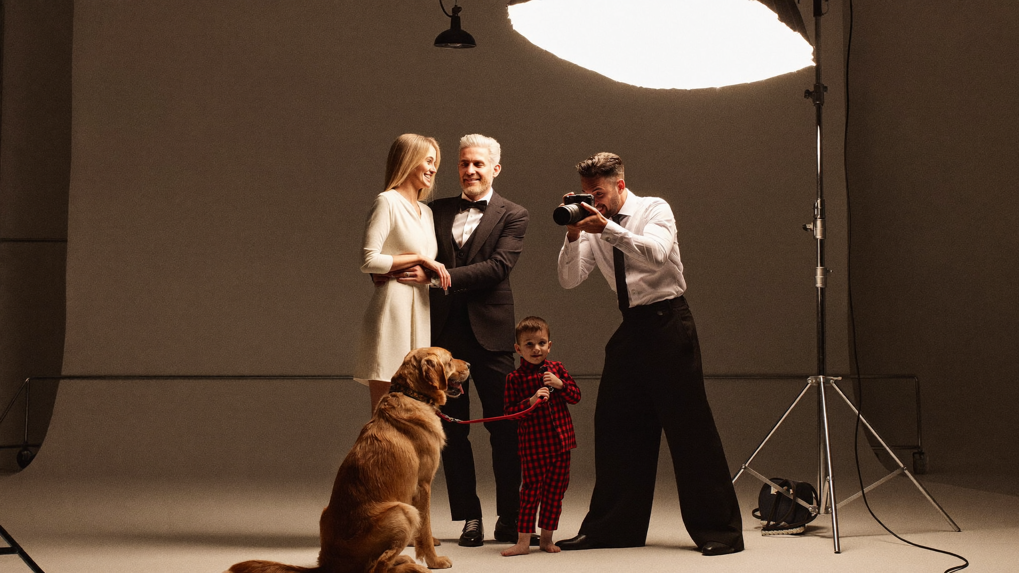 An elegant family with a golden retriever being photographed under a glowing softbox
