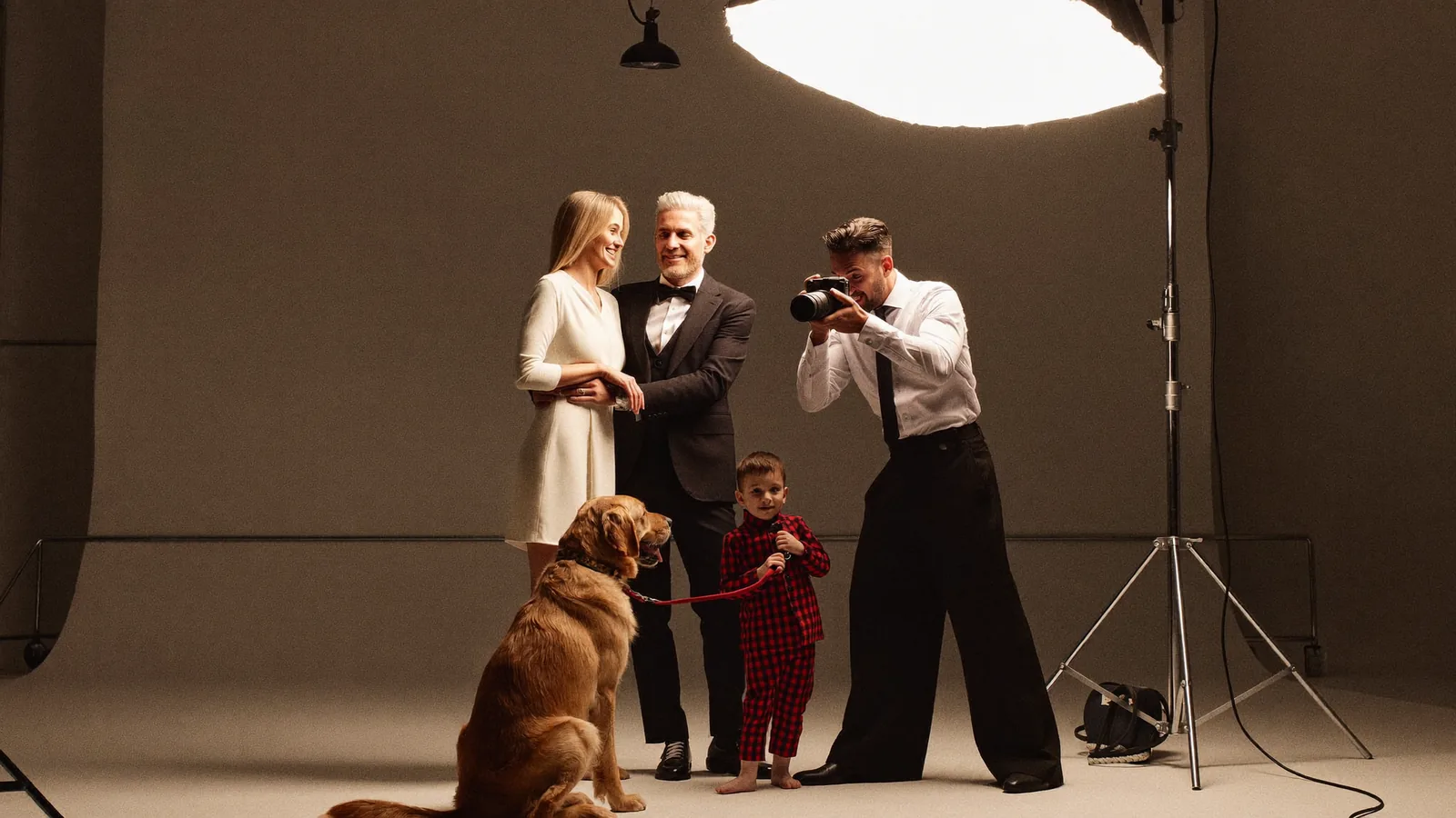 An elegant family with a golden retriever being photographed under a glowing softbox