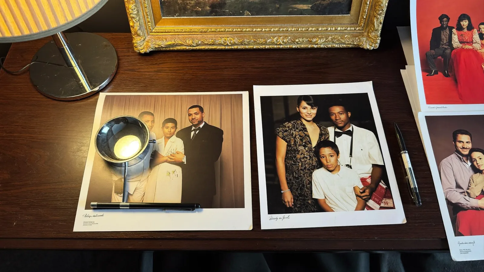 Signed studio portrait prints under a warm desk lamp with a loupe and fountain pen
